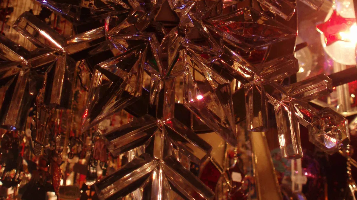 Close view of gold and red glass star ornaments hanging at a market stall