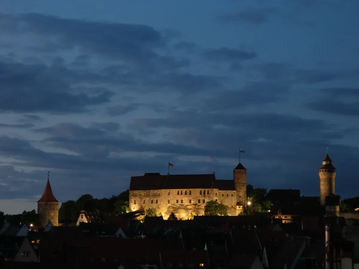 The Imperial Castle of Nuremberg lit at night above the old town roofs