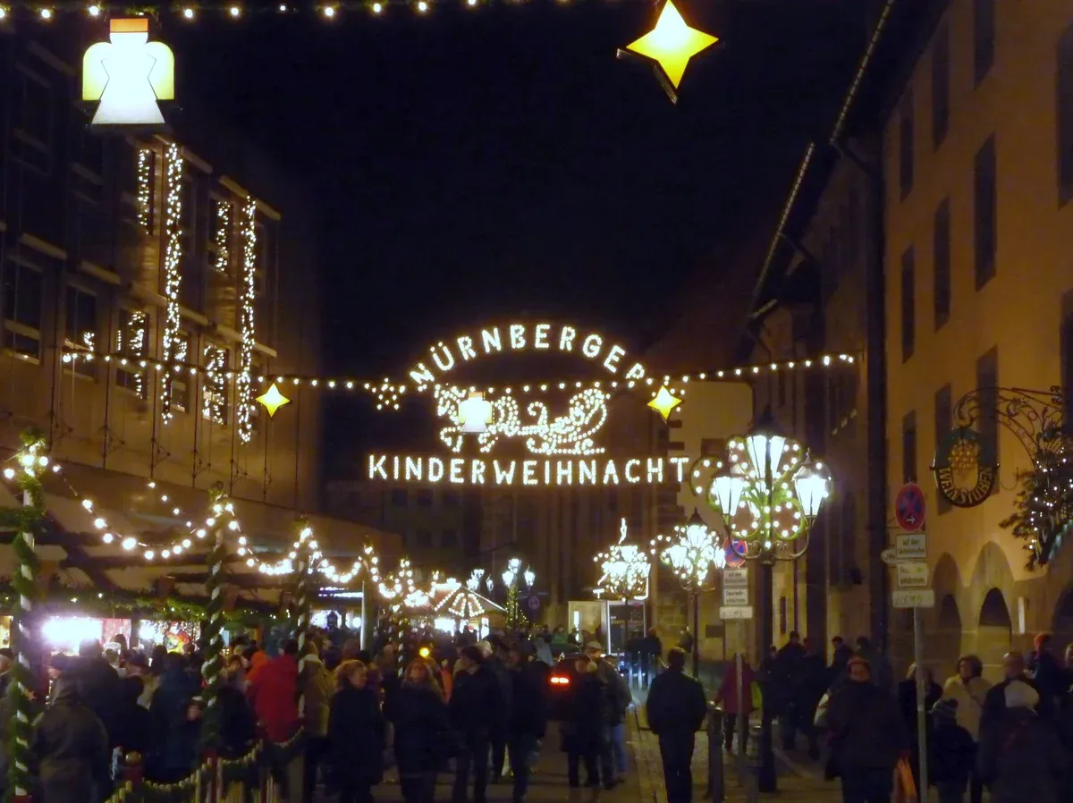 The lit arch reading Nürnberger Kinderweihnacht over the entrance to the children's market at night